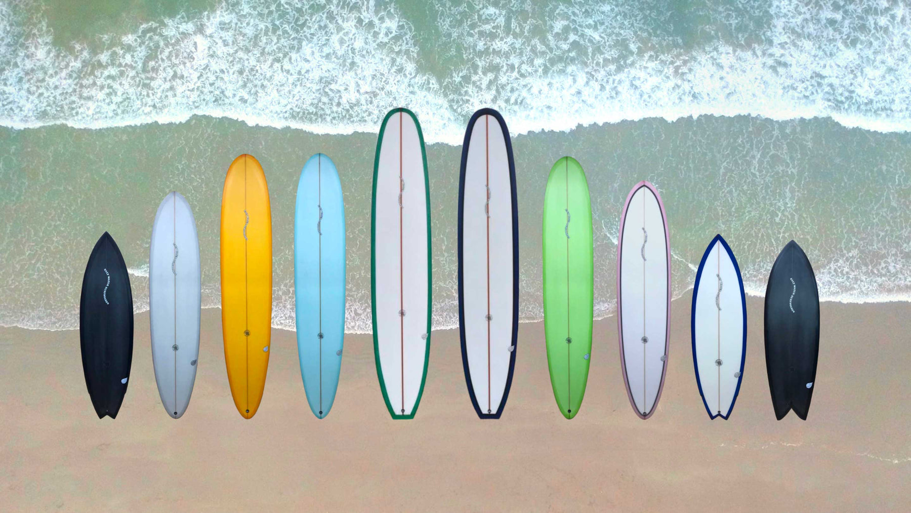 The image shows a collection of 10 Saltwater Surfboards out of the 40th anniversary edition. Part of this collection are short and longboards in different colors.